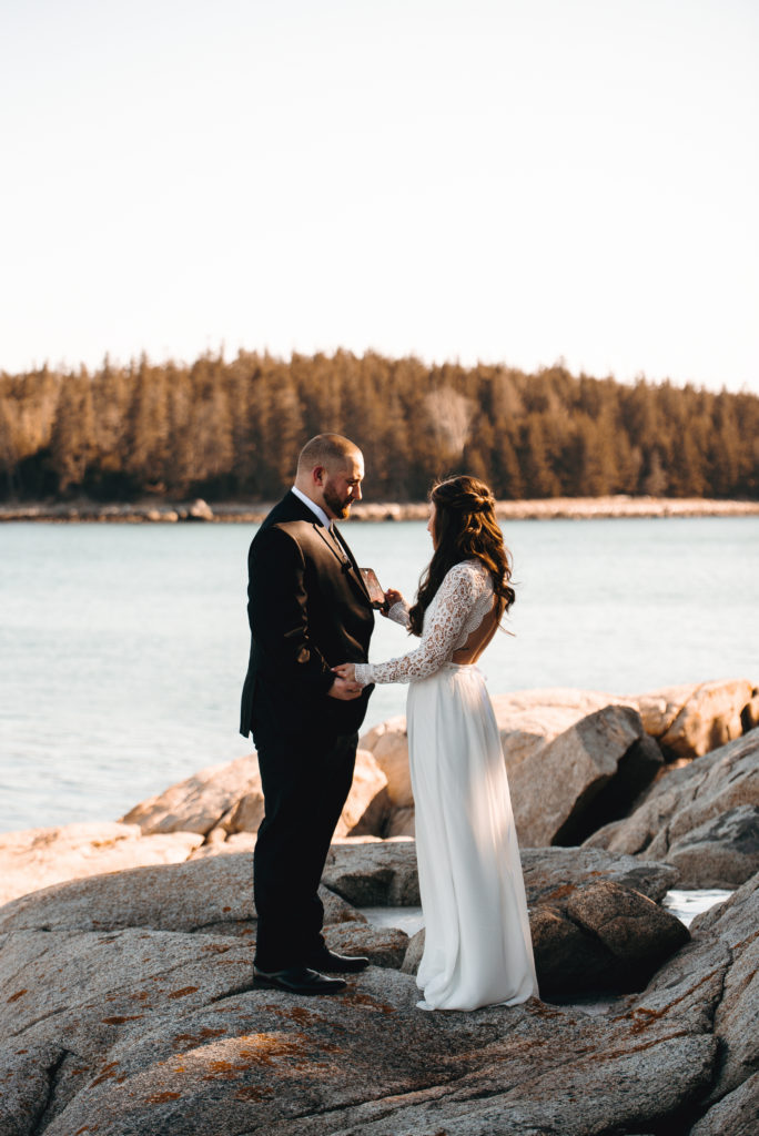 Groom holding bride's hand, bride is reading her vows. Couple is standing on the rocks beside the ocean on the coast of Owls Head, Maine at golden hour.
Owls Head, Maine elopement. Midcoast Maine wedding photographer. Maine elopement photographer. Maine adventure photographer.